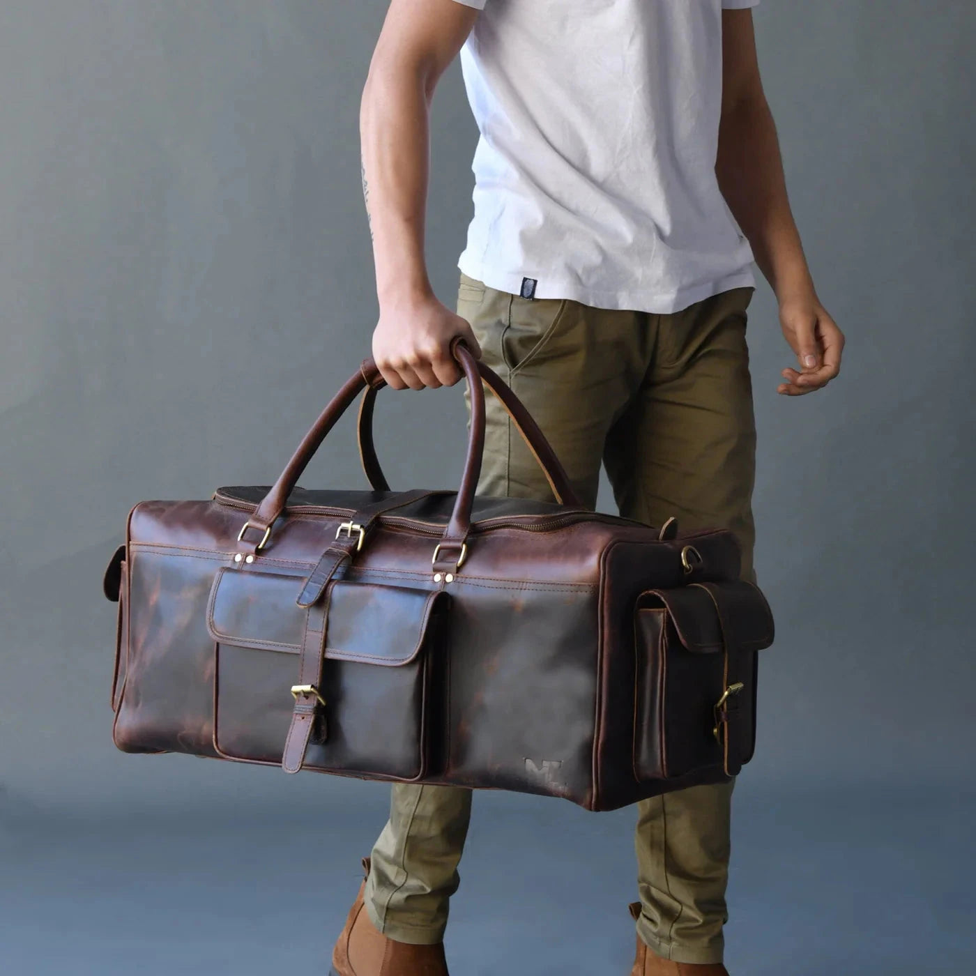 A person holding the Godzi Royal Duffle, a luxurious leather duffle bag suitable for travel.