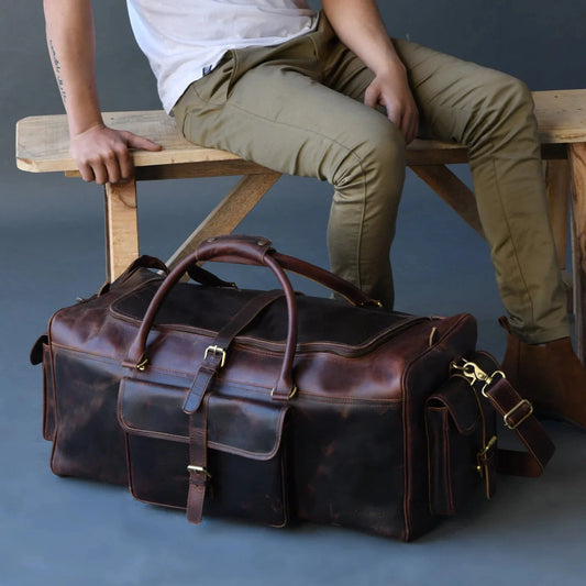 Godzi Royal Duffle leather duffle bag displayed alongside a person sitting on a wooden bench.